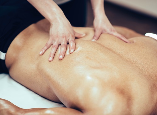 Man performing a sports massage on another man's back